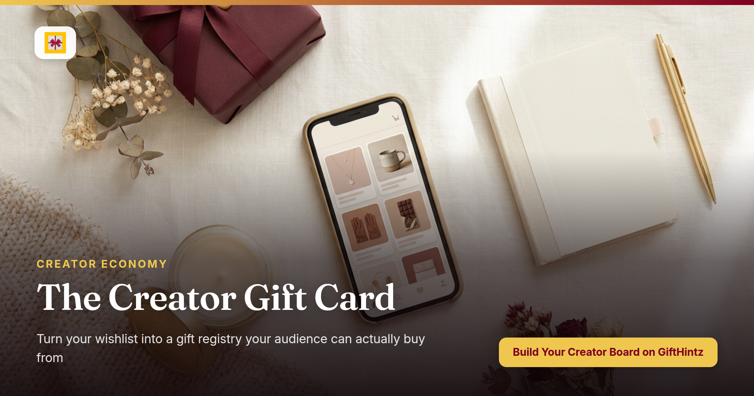 Flat lay of a smartphone showing a wishlist app surrounded by curated gifts: a burgundy-ribboned box, dried flowers, candle, and notebook on a warm cream linen surface
