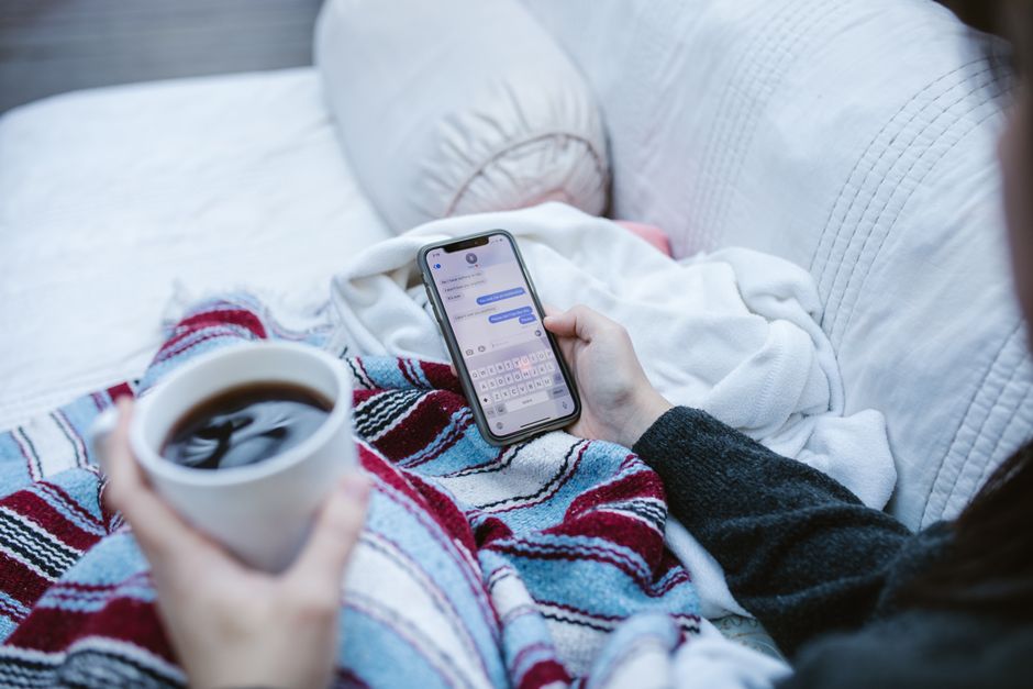 Person relaxing indoors with coffee and smartphone in a cozy setting — the feeling of having holiday shopping handled early